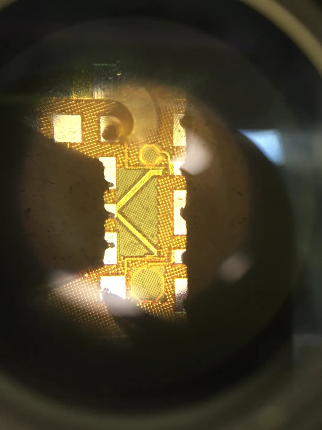 Microscope photograph of a bare silicon die showing metal layers and bond pads — representative of SMIC 28nm mature-node MPW output